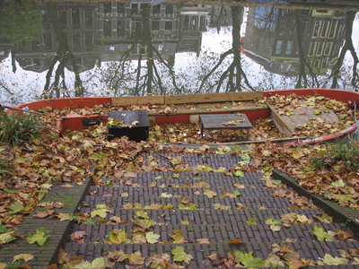 906082 Afbeelding van een sloep bedekt met herfstbladeren, aangemeerd bij de Van Asch van Wijckskade te Utrecht. Op de ...